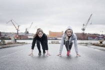 Two female running friends on their mark on dockside road — Stock Photo