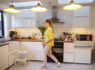 Mitte erwachsene Frau zu Fuß in stilvoller Küche — Stockfoto