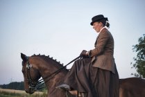 Средняя взрослая женщина верховая езда и тренировка выездной лошади в поле — стоковое фото