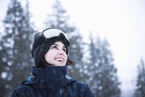 Portrait of young woman wearing ski goggles looking up at snow, Brighton Ski Resort outside of Salt Lake City, Utah, USA — Stock Photo