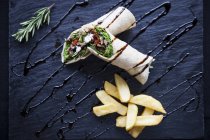 Top view of tortilla wraps with chips and sauce garnish on slate — Stock Photo