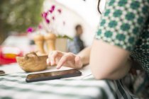 Cropped view of woman at pavement cafe using smartphone — Stock Photo