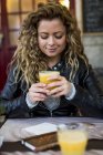 Жінка в кафе п'є апельсиновий сік — стокове фото