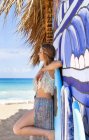 Young woman leaning against surfboard beach hut, Dominican Republic, The Caribbean — Stock Photo