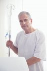 Portrait of senior male patient holding intravenous drip in hospital — Stock Photo