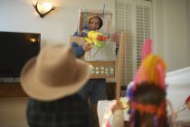 Uomo anziano in costume robot tiro pistole giocattolo con vestiti nipoti — Foto stock