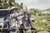 Man and teenage son on hiking road trip high fiving each other in landscape, Bridger, Montana, USA — Stock Photo