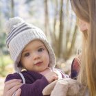 Retrato de bebé niña con sombrero de punto mirando a la cámara - foto de stock