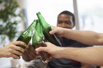 Manos de grupo de hombres haciendo un brindis con botellas de cerveza - foto de stock