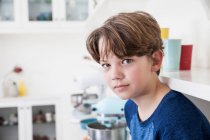 Портрет мальчика, сидящего на рабочей поверхности кухни — стоковое фото