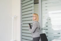 Зріла бізнес-леді тримає цифровий планшет покидає офіс — стокове фото