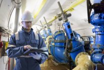 Arbeiter nimmt mit digitalem Tablet Messwerte in Stollen im Wasserkraftwerk auf — Stockfoto