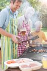 Family cooking kebabs and burgers on barbecue — Stock Photo