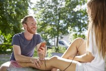 Young couple outdoors, listening to music through earphones — Stock Photo