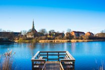 Veduta del molo di legno sul fiume e della guglia della chiesa lontana, Copenaghen, Danimarca — Foto stock