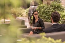 Geschäftsmann und Frau unterhalten sich auf Hotelgartensofa — Stockfoto