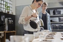 Дегустатор кофе наливает горячую воду в чашку кофе — стоковое фото