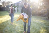 Happy family playing in garden together during cold weather — Stock Photo