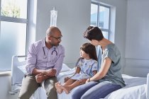 Male doctor talking to girl patient and her mother in hospital children's ward — Stock Photo