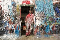 Художник-мужчина, прислонившийся к разбрызганным краской дверям — стоковое фото