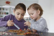 Girls at kitchen counter decorating cookies — Stock Photo