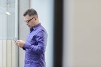 Male designer reading smartphone text in design studio — Stock Photo