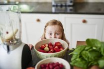 Menina espreitando tigelas de morangos de balcão de cozinha — Fotografia de Stock