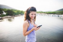 Frau schaut auf Handy am Meer — Stockfoto