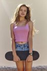 Portrait of teenage girl, outdoors, holding skateboard — Stock Photo