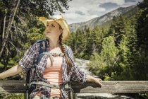 Young female hiker looking out from river footbridge, Red Lodge, Montana, USA — Stock Photo