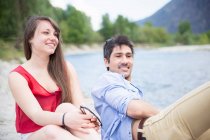 Giovane coppia seduta vicino al fiume — Foto stock