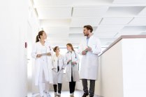 Male and female doctors walking in hospital corridor, talking — Stock Photo