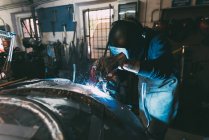 Trabajador del metal en la soldadura de la máscara de metal de soldadura en taller de forja - foto de stock