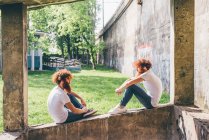 Молодые хипстеры-близнецы с рыжими бородами сидят на стене — стоковое фото