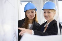 Geschäftsfrau zeigt auf Blaudruck in neuem Bürogebäude — Stockfoto