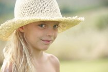 Portrait of young girl outdoors, wearing straw hat — Stock Photo