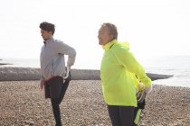 Entrenamiento de hombres y mujeres, de pie sobre una pierna en la playa de Brighton - foto de stock