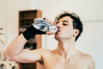 Чоловік п'є воду з пляшки в спортзалі — стокове фото
