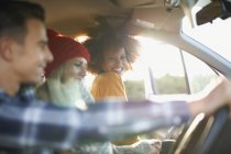 Three young adult friends in sunlit car — Stock Photo