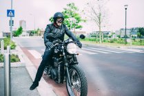 Зрелый мотоциклист, сидящий на мотоцикле на дороге — стоковое фото