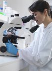 Científico observando muestras de tejido humano en microscopio en laboratorio — Stock Photo