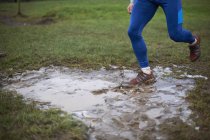 Ноги бегущего бегущего через грязную лужу — стоковое фото