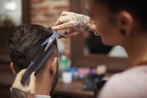 Coiffeur coupe les cheveux du client — Photo de stock