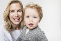 Porträt von Mutter und Sohn vor weißem Hintergrund, lächelnd — Stockfoto