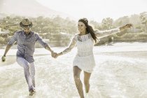 Couple running and splashing in sea, Cape Town, South Africa — Stock Photo