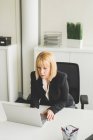 Madura mujer de negocios en el escritorio de la oficina utilizando ordenador portátil - foto de stock