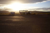 Camión turístico estacionado en el paisaje con montañas lejanas al amanecer, Islandia - foto de stock