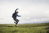 Männliche jugendliche Wanderer springen mitten in der Luft in Landschaft, cody, wyoming, usa — Stockfoto