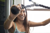 Frau im Fitnessstudio mit Trainingsgerät sieht lächelnd in die Kamera — Stockfoto