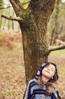 Молода дівчина, спираючись на дерево, очі закриті — стокове фото